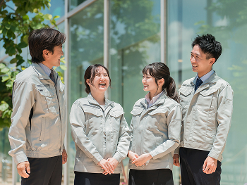 作業服を着た男女がビルの前で話している写真