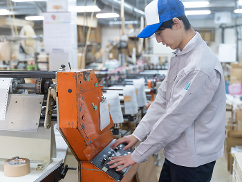 作業服の男性が工場内の機械を操作している写真